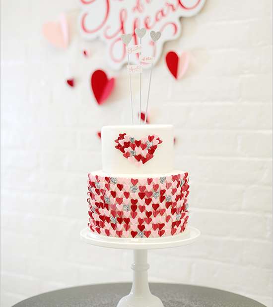 قالب الحلوى الأبيض المزيّن بالقلوب الحمراء الصغيرة يزيّن مائدة حفل العشاء برونق خاص 