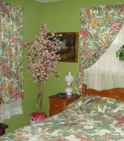 غرفة نوم تشبه الحديقة فغطاء السرير هو نفسه في الستائر، وشجرة ورد في غير مكانها تجعل الغرفة غير مريحة للنظر على الإطلاق