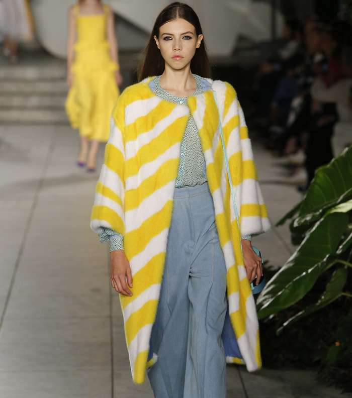 سروال الدنيم او الجينز الواسع مع قميص التول المنقط وسترة الفرو باللون الاصفر من كارولينا هيريرا لصيف 2018