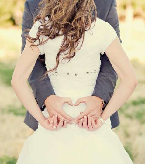 اطلبي من زوجك ان يضع يديه على خصرك على شكل قلب بينما تديرين ظهرك لمن يلتقط الصورة