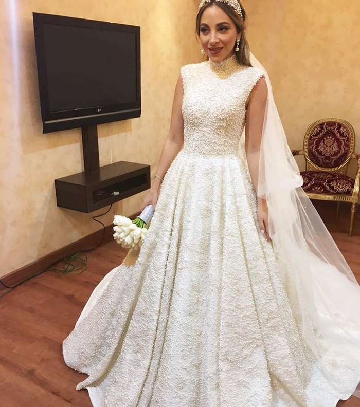 ثوب زفاف أنيق ومحتشم مرصّع باللؤلؤ للعروس