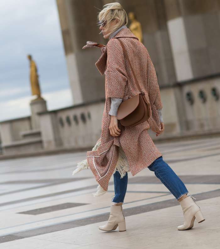 موضة معطف الكاب المزين بالشراريب على اطرافه مع حذاء الكاحل بلون البيج من شوارع باريس في اليوم الثاني من اسبوع الموضة الباريسي