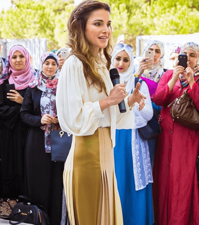الملكة رانيا ترتدي التنورة المثنية متوسطة الطول مع القميص المثني والحذاء الرسمي المروس من الامام
