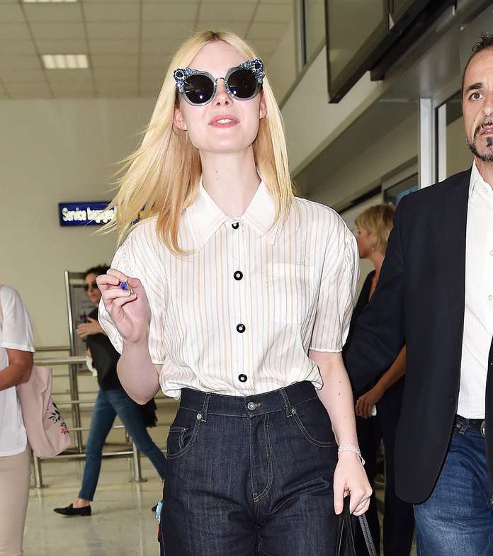 Elle Fanning تصل الى كان وهي ترتدي الجينز بقصة الوالدة مع القميص الكلاسيكي المقلم