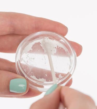 ثالثا: تفريغ البودرة في إناء صغيرة، وتغميش عود ثقاب تنظيف الأذنين به