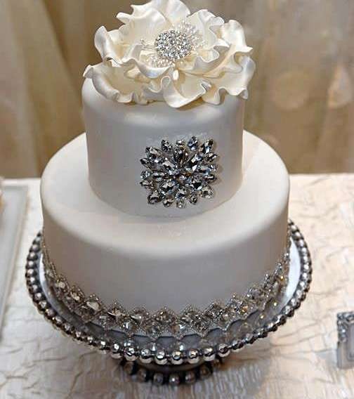 زينة كعكة الزفاف الفضيّة تنسجم مع لون الكريما عجينة السكّر البيضاء 
