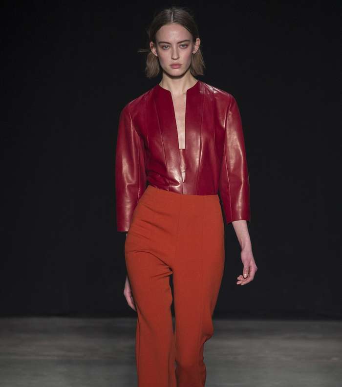 السروال البرتقالي بقصة الـ Flare مع التوب الجلدية باللون الاحمر النبيذي والقصة المنخفضة على الصدر من نارسيزو رودريغيز لشتاء 2018