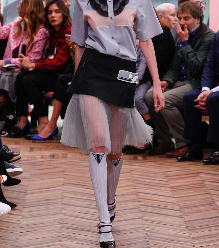 القميص الكلاسيكي مع ياقة مثنية وتنورة مثنية وفوقها تنورة قصيرة مستقمية من برادا من مجموعة Resort 2018